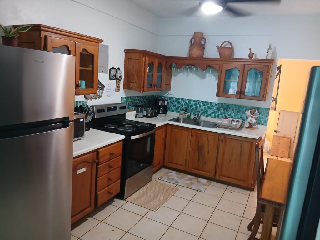 Bona Villa, Bon Accord, Tobago: the fully equipped kitchen, with a fridge freezer, cooker and wooden cabinets.