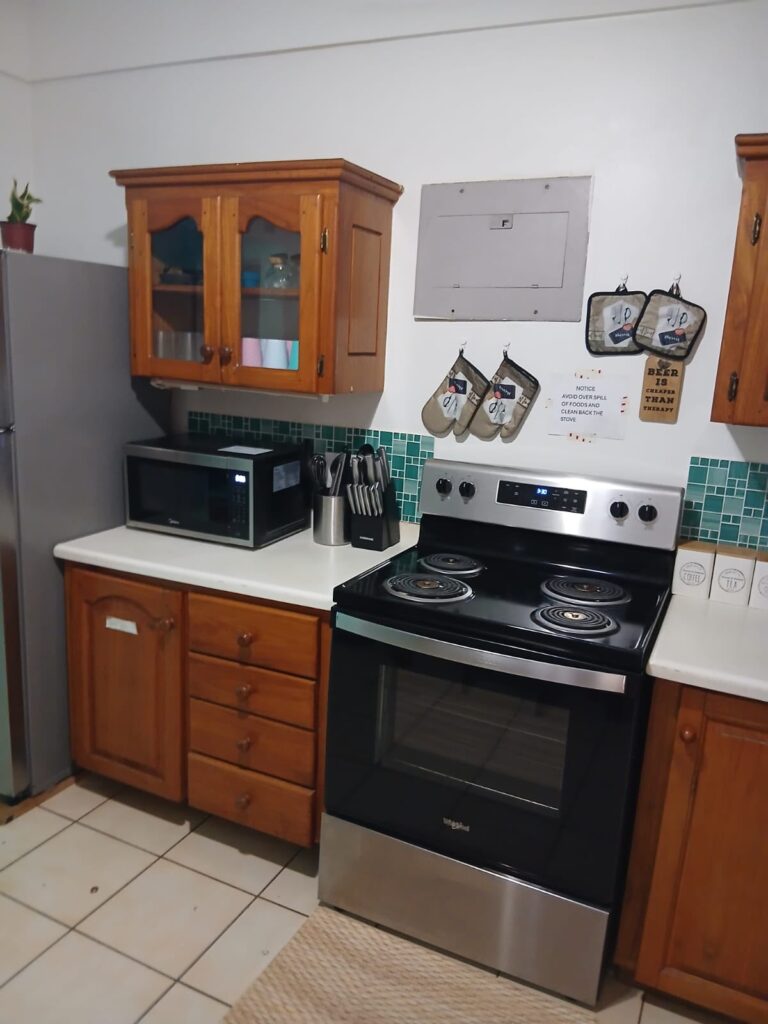 Bona Villa, Bon Accord, Tobago: the kitchen cooker and microwave, with a tiled splashback.