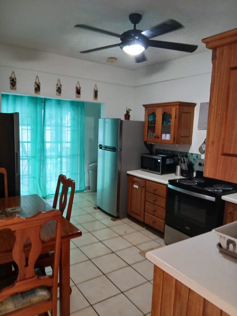 Bona Villa, Bon Accord, Tobago: the kitchen seen from the dining table, with the cooker and fridge beyond.