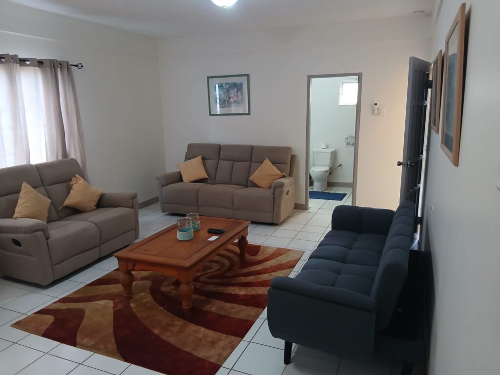 Bona Villa, Bon Accord, Tobago: the living room, with recliner seating and an en-suite beyond.