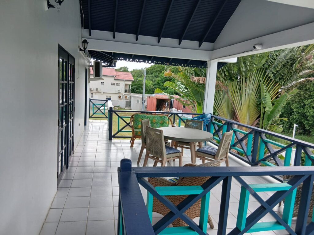 Bona Villa, Bon Accord, Tobago: the covered upstairs verandah, with a dining table and wicker seating.